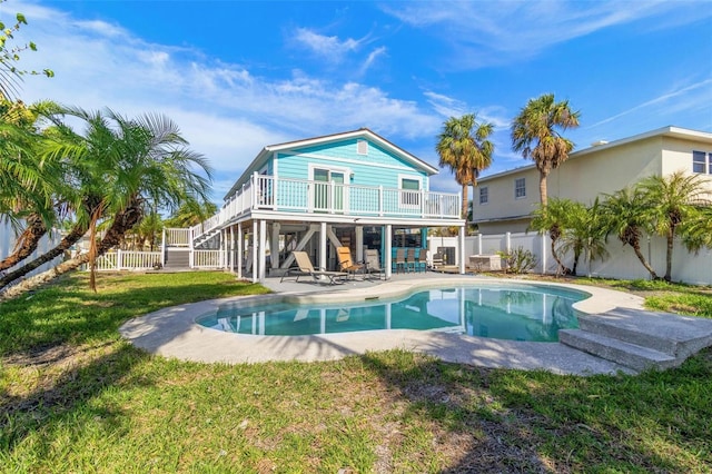 back of house featuring a lawn, a pool side deck, and a patio