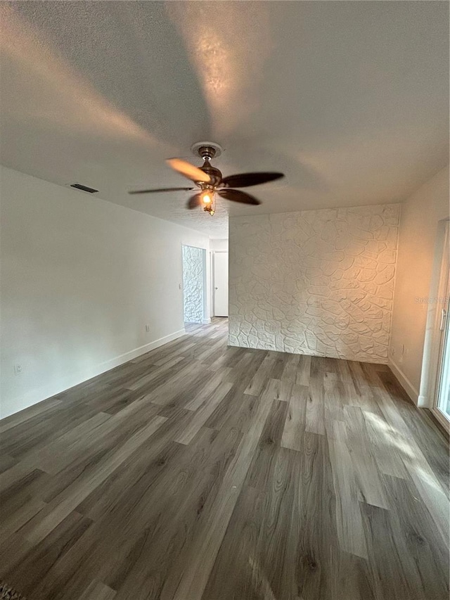 empty room featuring a textured ceiling, hardwood / wood-style flooring, and ceiling fan