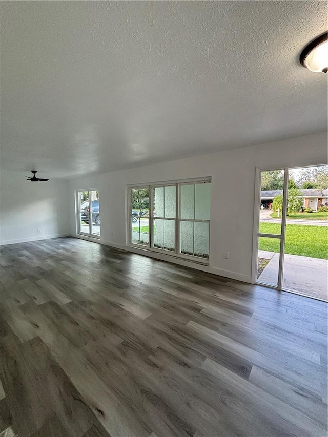 unfurnished living room featuring a textured ceiling and dark hardwood / wood-style floors