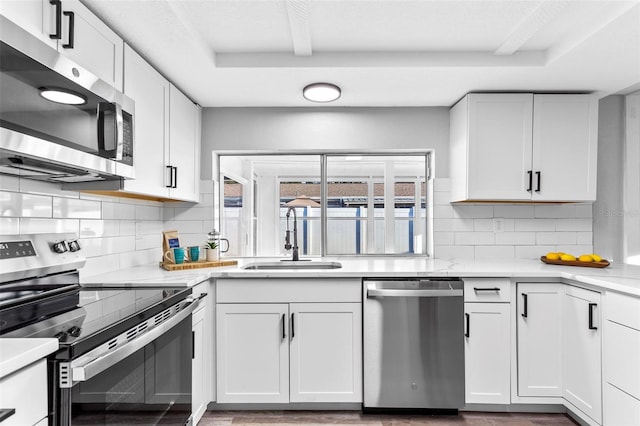 kitchen featuring appliances with stainless steel finishes, white cabinetry, backsplash, and sink