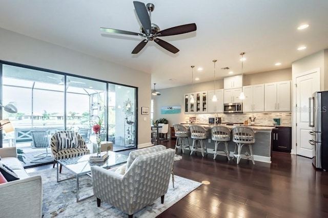 living room featuring ceiling fan and dark wood-type flooring