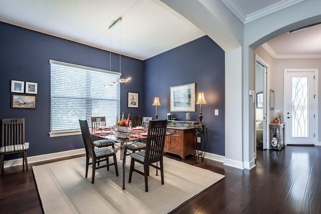 dining space featuring dark hardwood / wood-style flooring, ornamental molding, and a chandelier