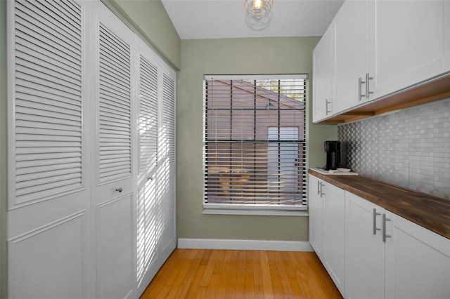 interior space with white cabinetry, tasteful backsplash, light hardwood / wood-style flooring, butcher block countertops, and a textured ceiling