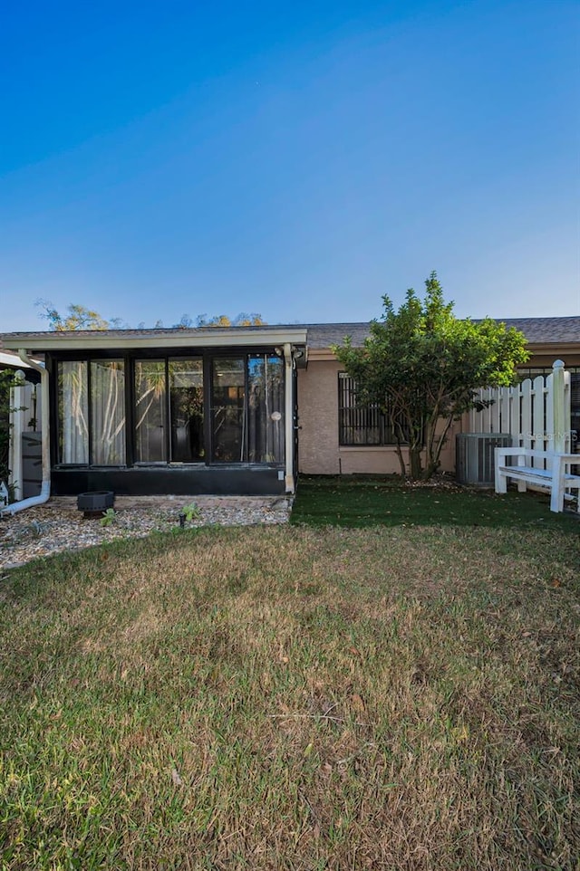 rear view of house featuring a lawn and a sunroom