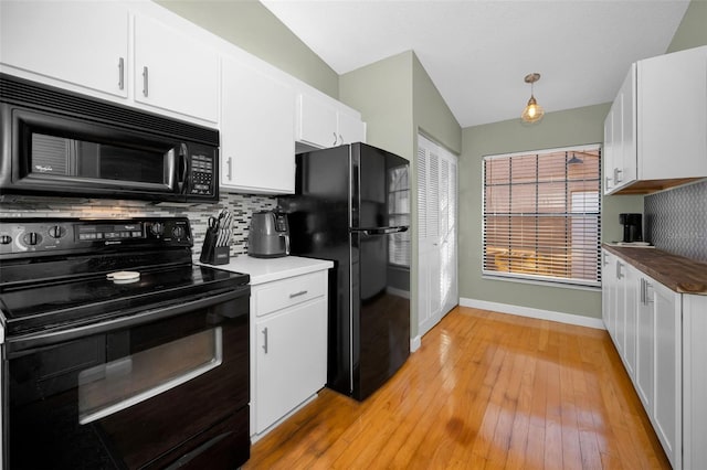 kitchen with white cabinets, black appliances, and vaulted ceiling