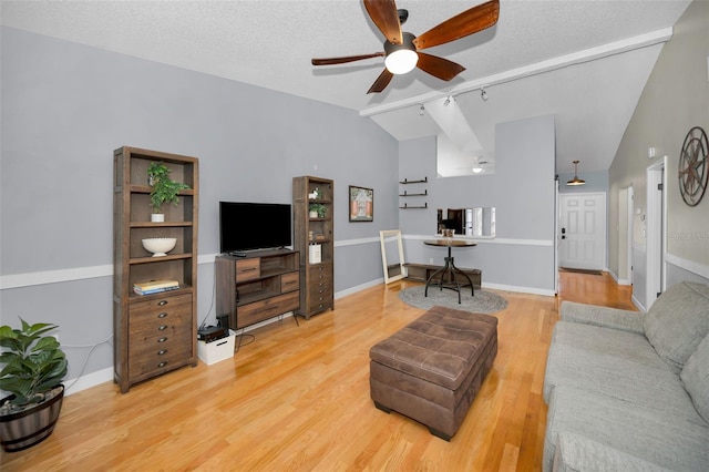 living room featuring high vaulted ceiling, rail lighting, hardwood / wood-style flooring, ceiling fan, and a textured ceiling