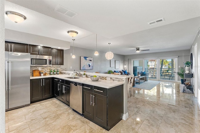 kitchen featuring kitchen peninsula, appliances with stainless steel finishes, hanging light fixtures, and ceiling fan