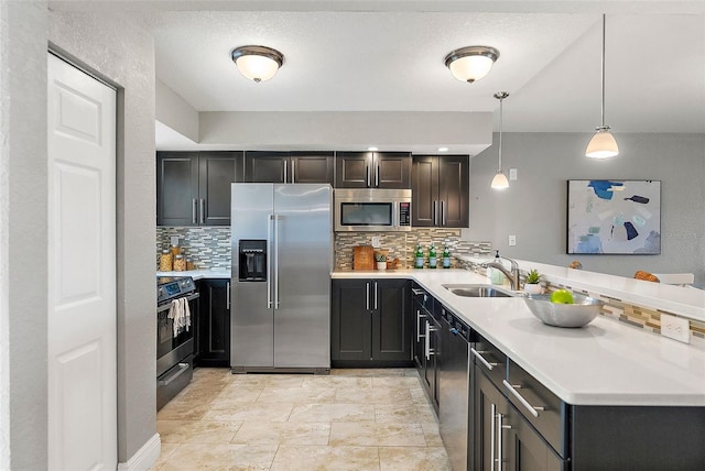 kitchen with kitchen peninsula, tasteful backsplash, stainless steel appliances, sink, and decorative light fixtures