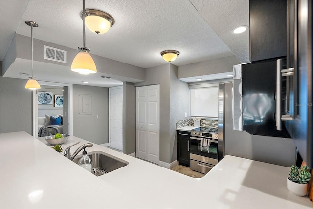 kitchen featuring tasteful backsplash, stainless steel range, a textured ceiling, sink, and decorative light fixtures