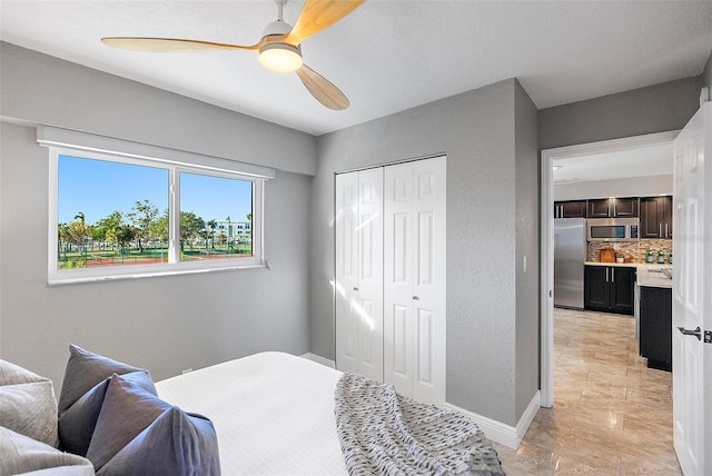 bedroom featuring stainless steel refrigerator, ceiling fan, and a closet