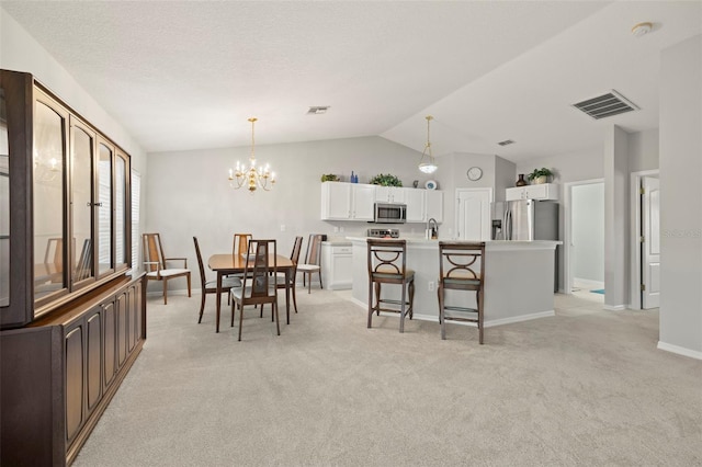 carpeted dining room with sink, a chandelier, and lofted ceiling