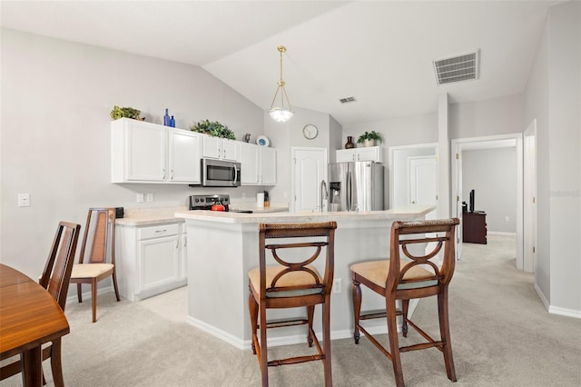 kitchen featuring light carpet, a kitchen island, stainless steel appliances, and vaulted ceiling