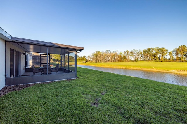 view of yard featuring a sunroom and a water view