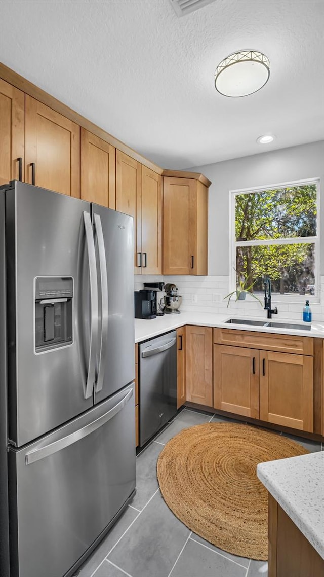 kitchen featuring decorative backsplash, a textured ceiling, stainless steel appliances, and sink