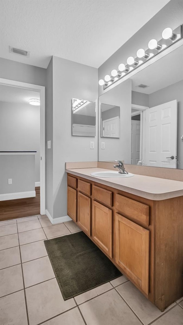 bathroom with a textured ceiling, vanity, and tile patterned floors