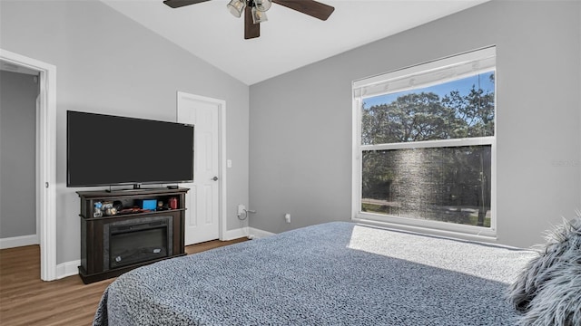 bedroom featuring hardwood / wood-style floors, ceiling fan, vaulted ceiling, and multiple windows