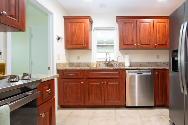 kitchen featuring light stone countertops, appliances with stainless steel finishes, light tile patterned floors, and sink