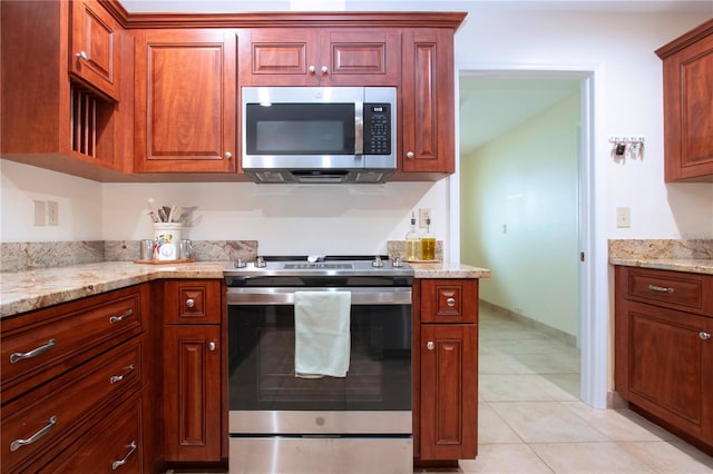 kitchen with light tile patterned floors, stainless steel appliances, and light stone counters