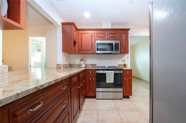 kitchen featuring kitchen peninsula, appliances with stainless steel finishes, light tile patterned floors, and light stone counters