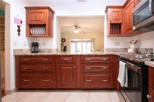 kitchen with ceiling fan, light stone counters, light tile patterned floors, and stainless steel appliances