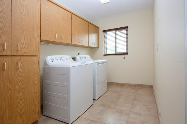 washroom featuring cabinets, light tile patterned floors, and washing machine and clothes dryer