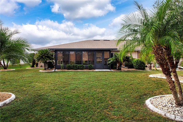 rear view of property featuring a sunroom and a yard