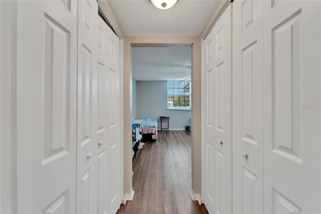 hall featuring a textured ceiling and dark hardwood / wood-style floors