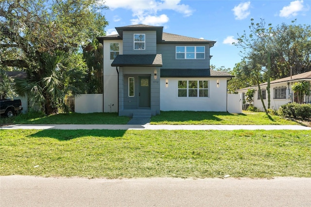 view of front of property featuring roof with shingles, fence, and a front yard