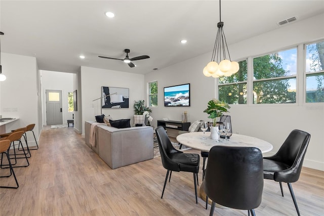 dining area featuring light hardwood / wood-style flooring and ceiling fan with notable chandelier