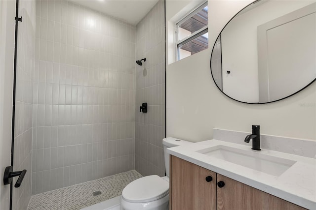 bathroom with tiled shower, vanity, and toilet