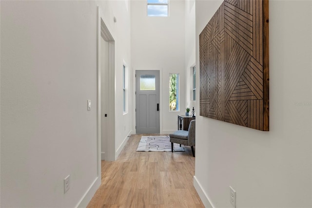 corridor featuring light hardwood / wood-style flooring and a high ceiling