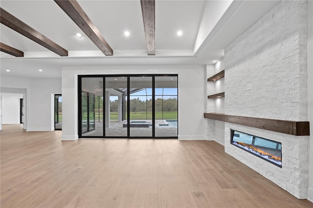 unfurnished living room with a stone fireplace, recessed lighting, wood finished floors, baseboards, and beamed ceiling