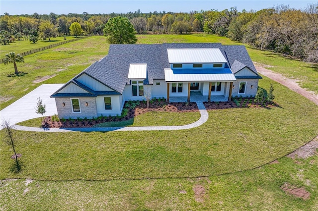 modern farmhouse style home with a front yard, a standing seam roof, metal roof, and driveway