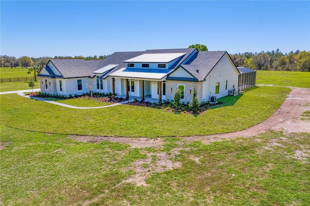 modern farmhouse with a porch, a front yard, a standing seam roof, metal roof, and fence