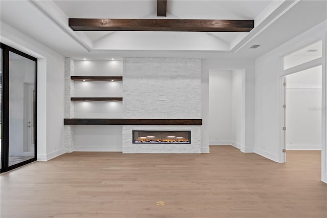 unfurnished living room with vaulted ceiling with beams, baseboards, wood finished floors, and a stone fireplace