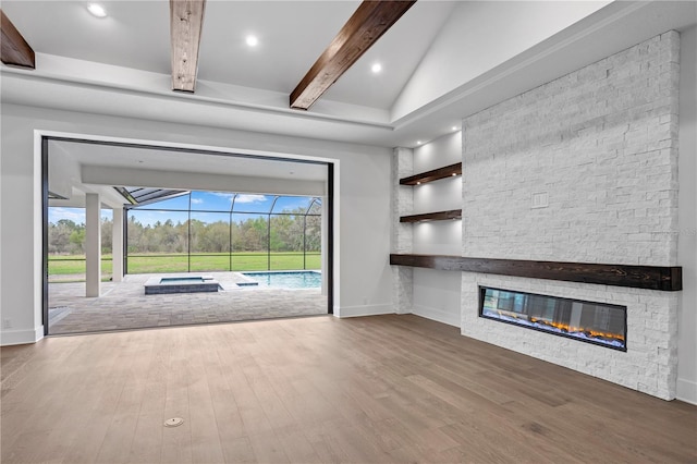 unfurnished living room featuring beam ceiling, a sunroom, a stone fireplace, wood finished floors, and baseboards