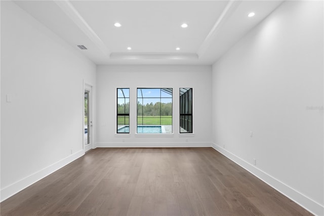 unfurnished room with a tray ceiling, dark wood-style flooring, visible vents, and baseboards