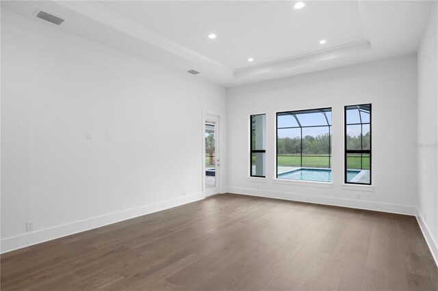 spare room with dark wood-style floors, recessed lighting, a raised ceiling, visible vents, and baseboards