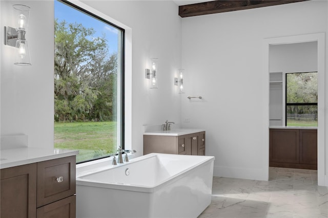 full bathroom featuring beam ceiling, marble finish floor, a soaking tub, vanity, and baseboards