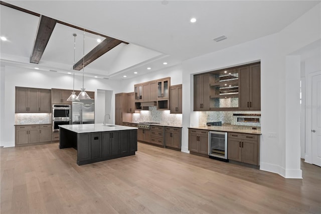 kitchen with light wood-style flooring, wine cooler, appliances with stainless steel finishes, light countertops, and a sink