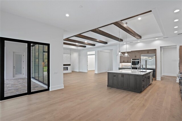 kitchen featuring open floor plan, stainless steel appliances, light wood finished floors, and light countertops