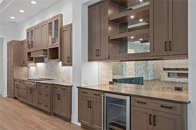 kitchen with wine cooler, stainless steel gas cooktop, open shelves, light wood-style floors, and extractor fan