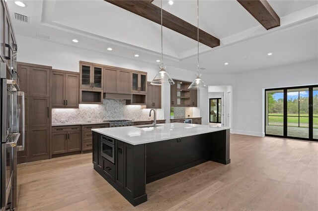 kitchen with a sink, light countertops, open shelves, tasteful backsplash, and beamed ceiling