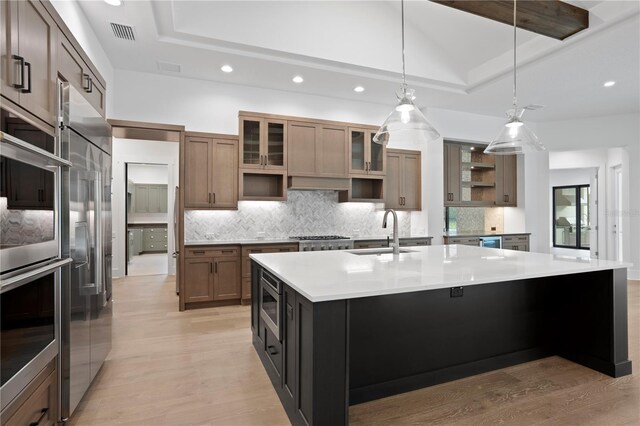 kitchen with a large island, visible vents, a raised ceiling, and a sink