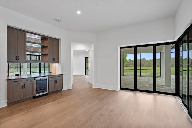 bar with wine cooler, baseboards, visible vents, and light wood finished floors