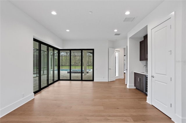 empty room featuring light wood-type flooring, visible vents, and recessed lighting