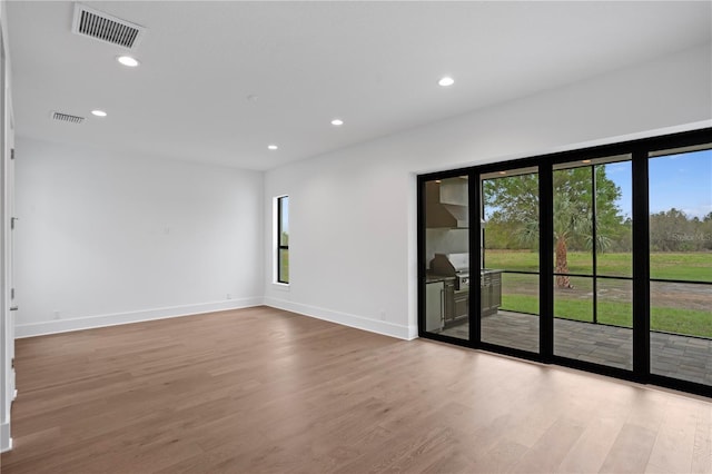 spare room with visible vents, a wealth of natural light, and wood finished floors