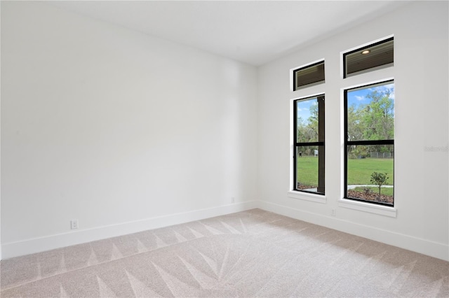 unfurnished room featuring light carpet and baseboards