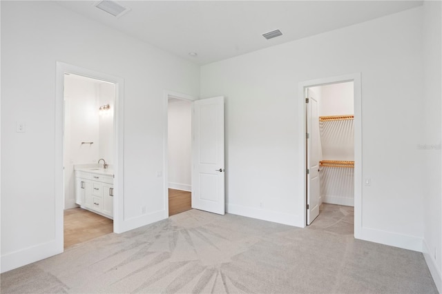 unfurnished bedroom featuring light carpet, baseboards, visible vents, and a sink