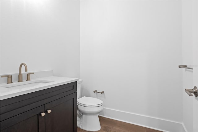 bathroom featuring baseboards, vanity, toilet, and wood finished floors